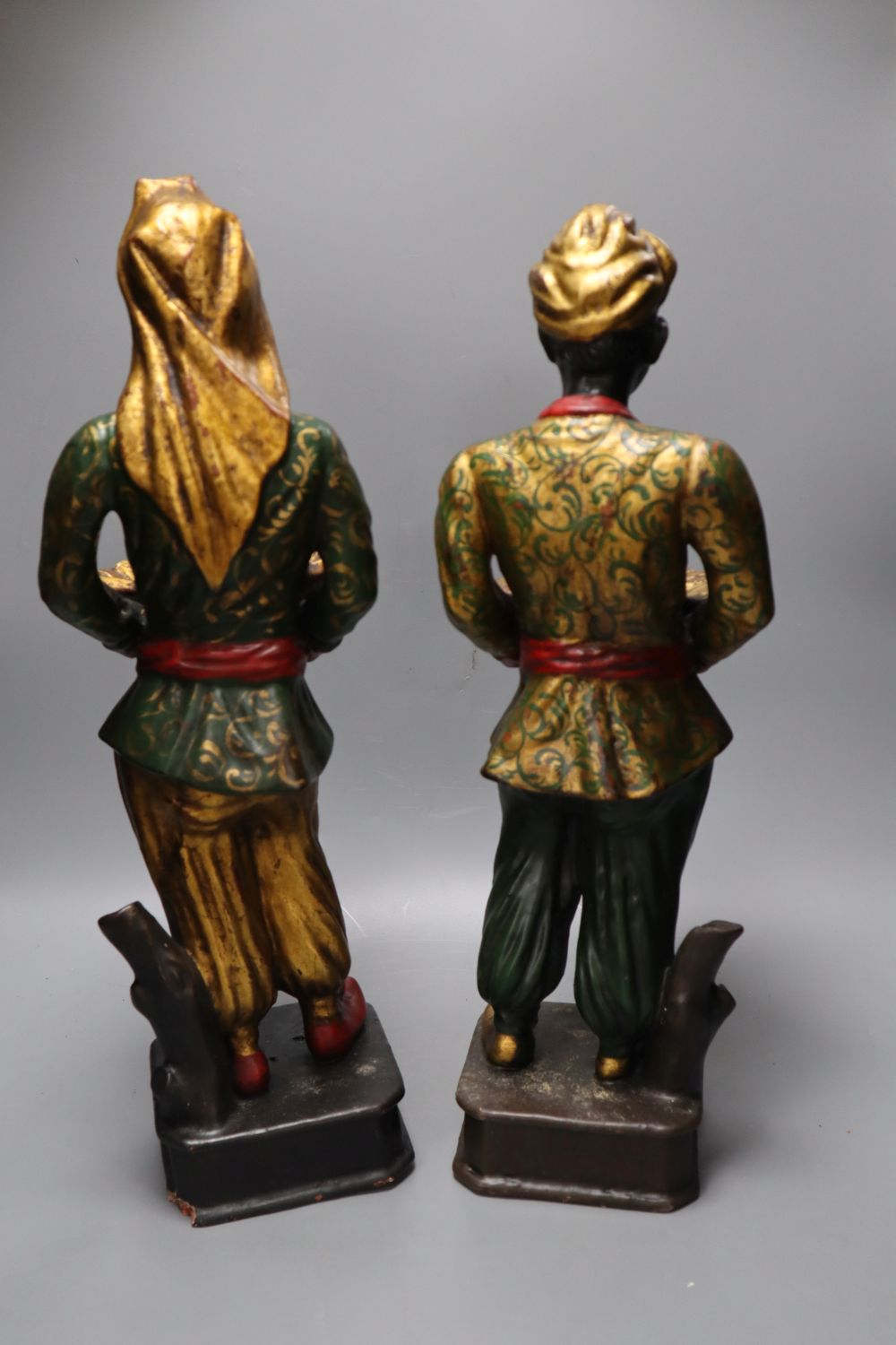 A pair of gilt and polychrome painted Nubian butlers, portrayed holding shell shaped trays
